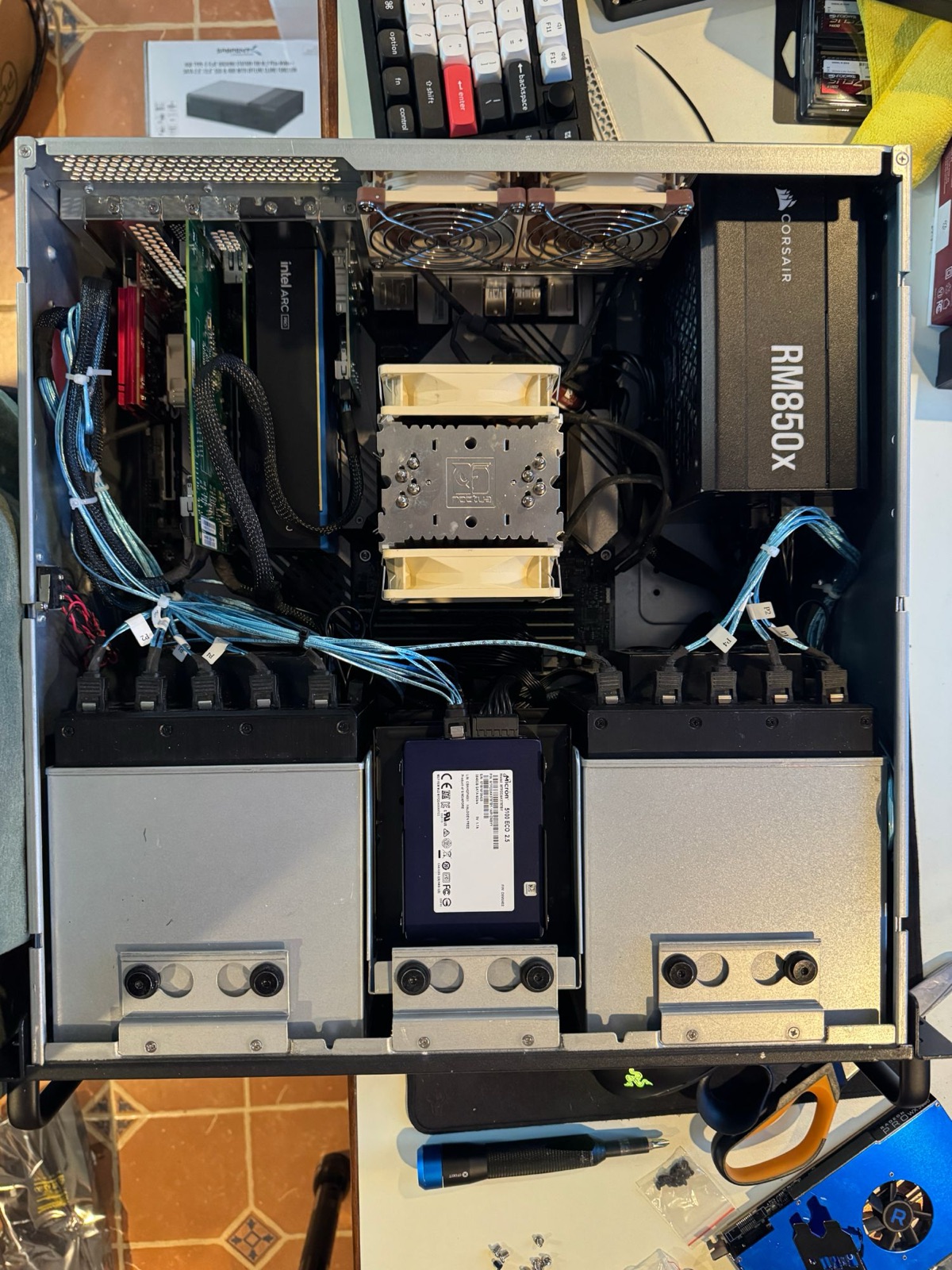 Server chassis interior showing Noctua CPU cooler, Corsair RM850x power supply, Intel Arc Pro GPU, and dual hot-swap drive cages with routed SATA cabling